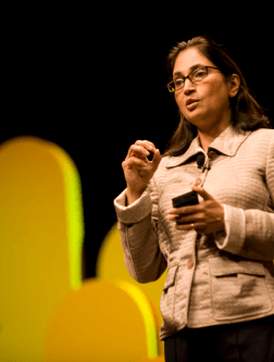 A woman speaking while holding her phone. 